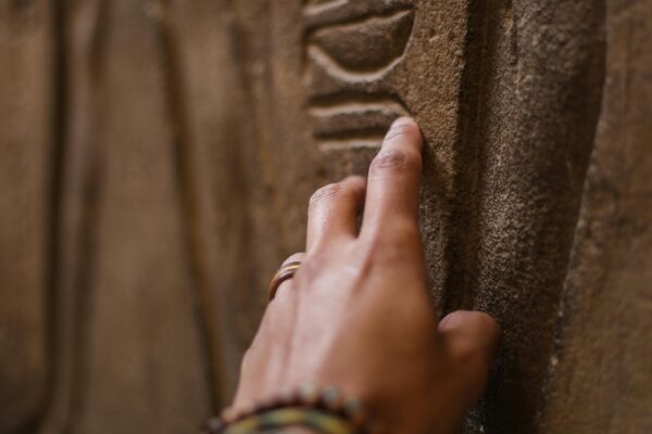 Tomb of the Ancients: 5,000-Year-Old Neolithic Burial Site Unearthed in Orkney, Scotland Close-up of a hand touching ancient hieroglyphics on a sandstone wall during an exploration.
