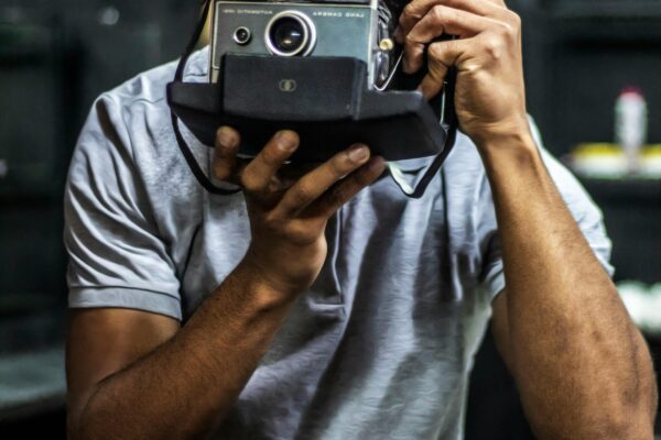 Defense Secretary Pete Hegseth on the Brink: White House Considers Replacement Amid Classified Leak Scandal Young adult using a classic vintage camera indoors, focused on photography.