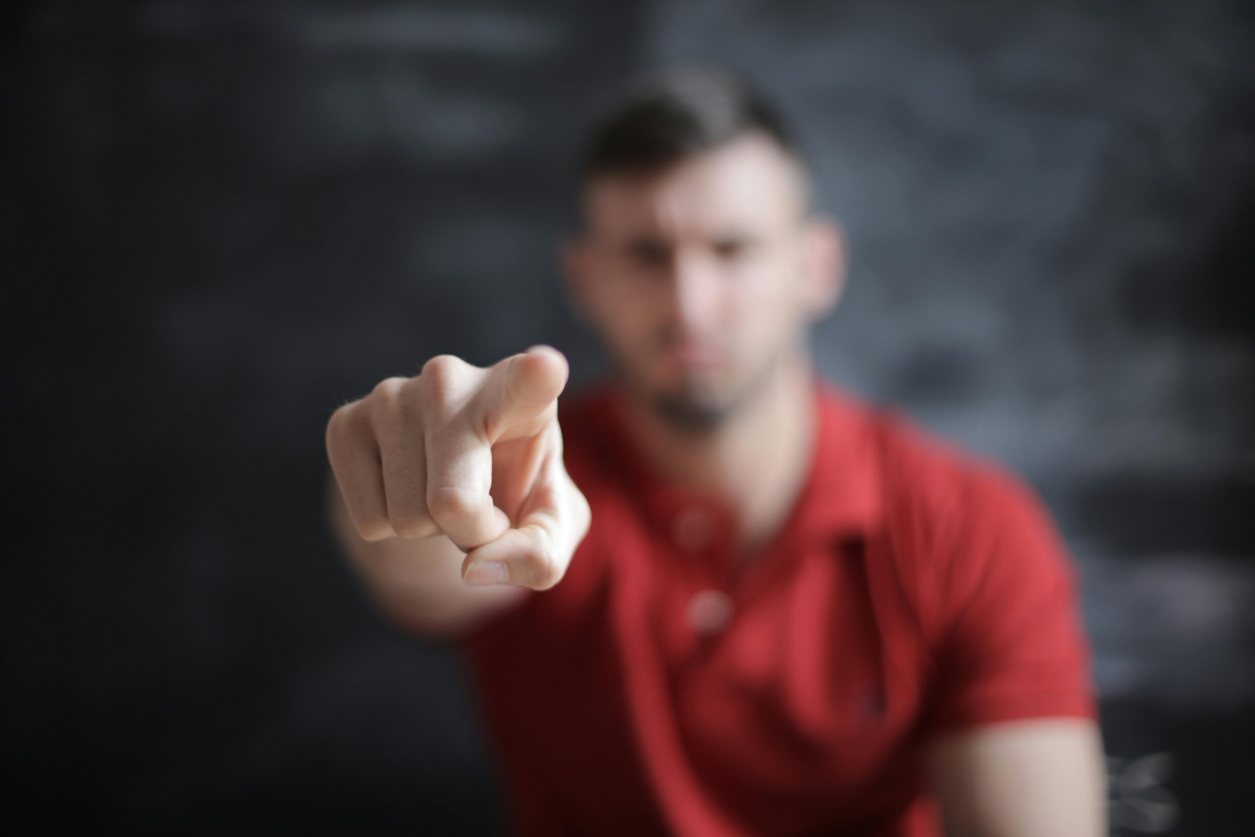 Blurred man pointing forward, emphasizing index finger close-up.