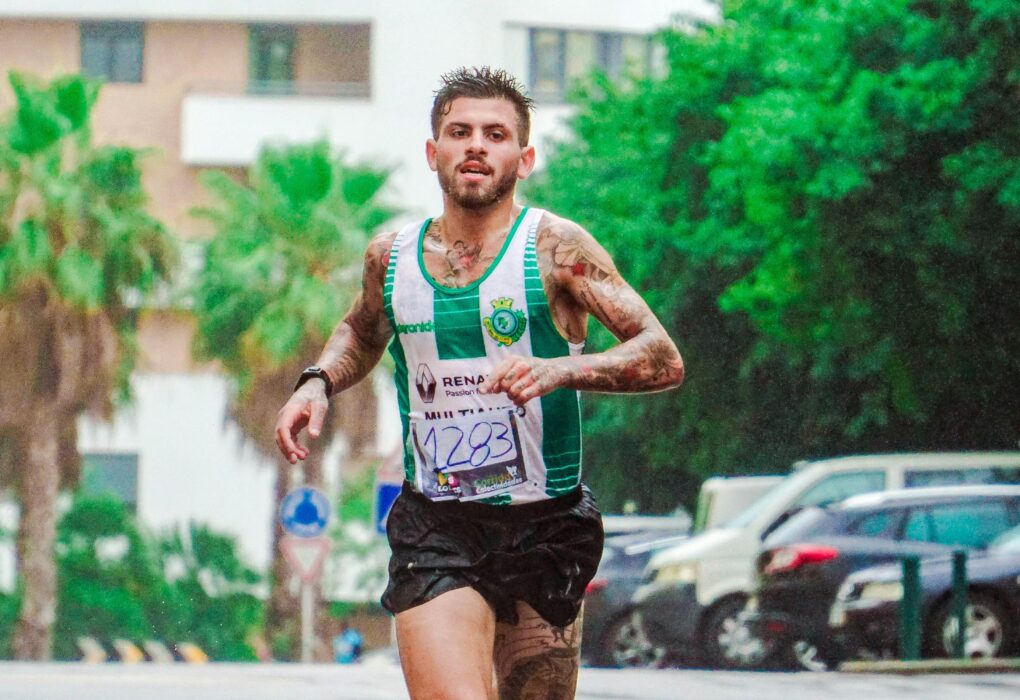 Tattooed male runner participating in a marathon, showing dedication and endurance on a rainy day.