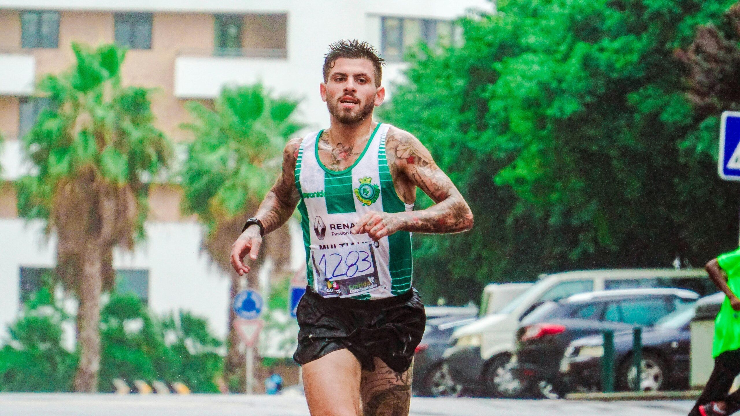 Tattooed male runner participating in a marathon, showing dedication and endurance on a rainy day.