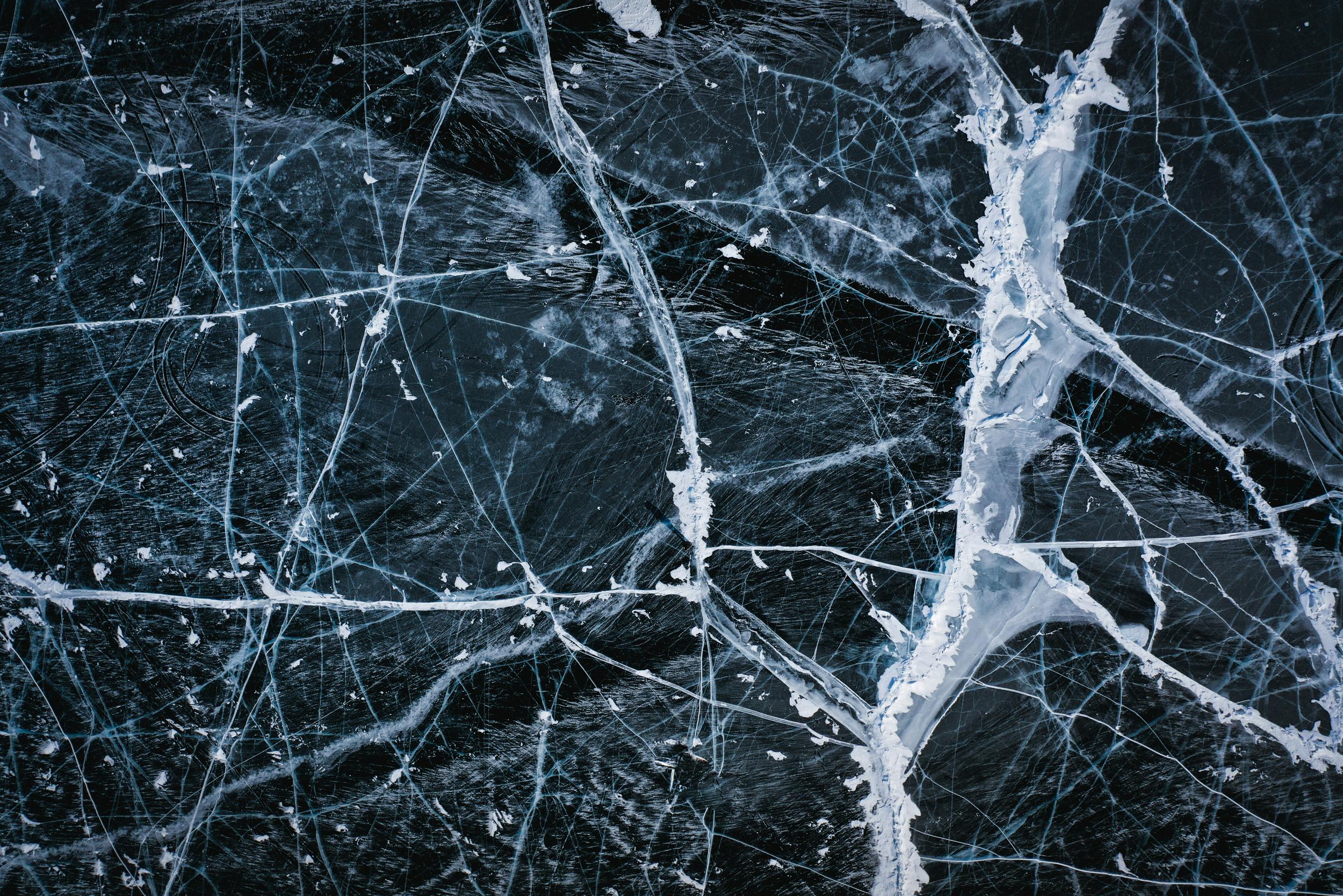Aerial view of intricate ice cracks on Lake Baikal's surface, showcasing winter's beauty.